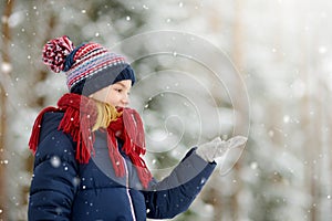 Adorable little girl having fun in beautiful winter park. Cute child playing in a snow.