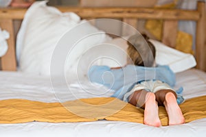 Adorable little girl having fun at home and lying in big family bead