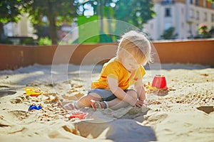 Adorable little girl having fun on playground in sandpit