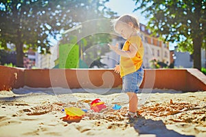 Adorable little girl having fun on playground in sandpit