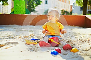 Adorable little girl having fun on playground in sandpit