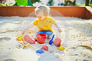 Adorable little girl having fun on playground in sandpit