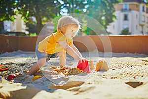 Adorable little girl having fun on playground in sandpit