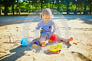 Adorable little girl having fun on playground in sandpit