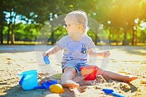 Adorable little girl having fun on playground in sandpit