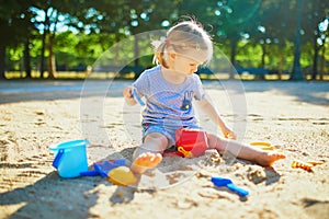 Adorable little girl having fun on playground in sandpit