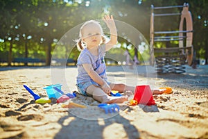 Adorable little girl having fun on playground in sandpit