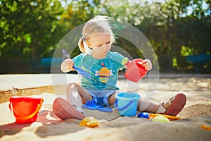 Adorable little girl having fun on playground in sandpit