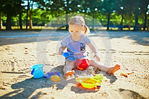 Adorable little girl having fun on playground in sandpit