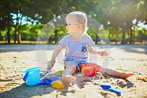 Adorable little girl having fun on playground in sandpit