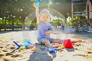 Adorable little girl having fun on playground in sandpit