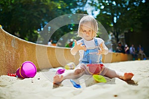 Adorable little girl having fun on playground in sandpit