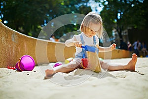 Adorable little girl having fun on playground in sandpit