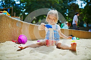 Adorable little girl having fun on playground in sandpit