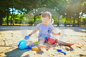 Adorable little girl having fun on playground in sandpit