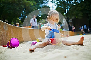 Adorable little girl having fun on playground in sandpit