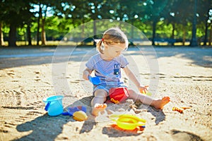 Adorable little girl having fun on playground in sandpit