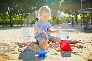 Adorable little girl having fun on playground in sandpit