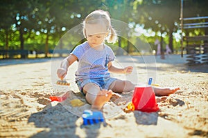 Adorable little girl having fun on playground in sandpit