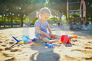 Adorable little girl having fun on playground in sandpit