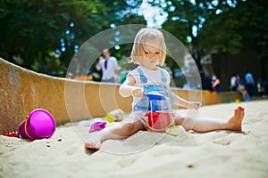 Adorable little girl having fun on playground in sandpit