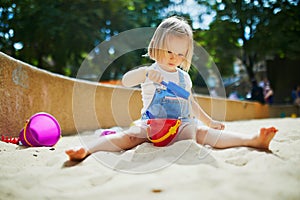 Adorable little girl having fun on playground in sandpit