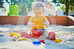 Adorable little girl having fun on playground in sandpit photo