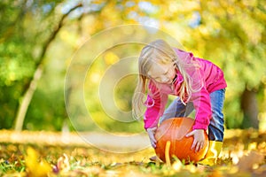 Adorable little girl having fun on a pumpkin patch on beautiful autumn day