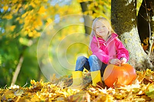 Adorable little girl having fun on a pumpkin patch on beautiful autumn day