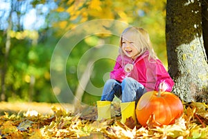 Adorable little girl having fun on a pumpkin patch on beautiful autumn day