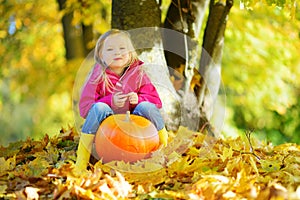 Adorable little girl having fun on a pumpkin patch on beautiful autumn day