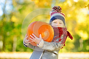 Adorable little girl having fun on a pumpkin patch on beautiful autumn day