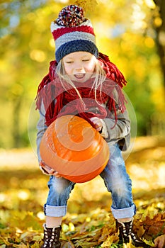 Adorable little girl having fun on a pumpkin patch on beautiful autumn day