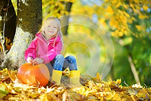 Adorable little girl having fun on a pumpkin patch on beautiful autumn day