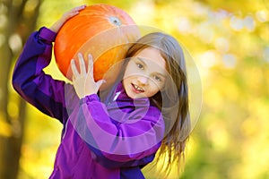 Adorable little girl having fun on a pumpkin patch on beautiful autumn day