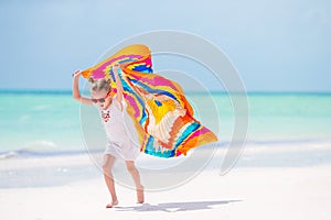 Adorable little girl having fun running with pareo on tropical white beach