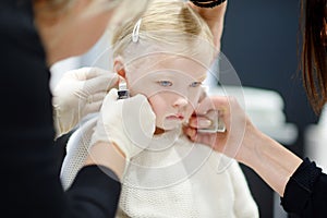 Adorable little girl having her ears pierced