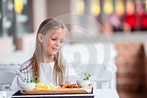 Adorable little girl having lunch at outdoor cafe