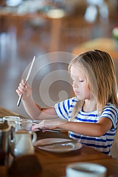 Adorable little girl having lunch in outdoor cafe