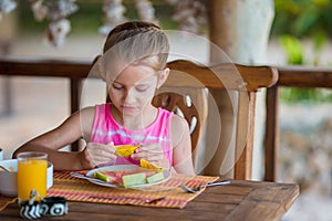 Adorable little girl having lunch at outdoor cafe