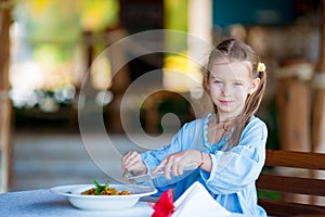 Adorable little girl having lunch at outdoor cafe