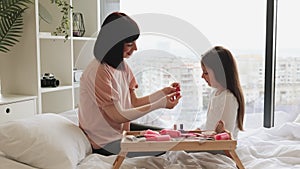 Adorable little girl with her mother in casual wear paint their fingernails.