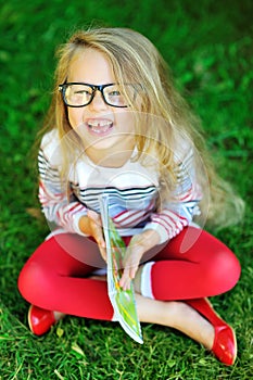 Adorable little girl holding book and laughing