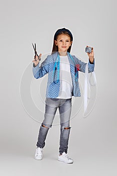 Adorable little girl holding tape measure and spool of thread