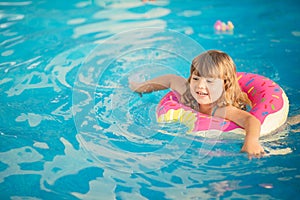 Adorable little girl with inflatable life vest having fun in the pool