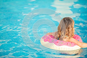 Adorable little girl with inflatable life vest having fun in the pool