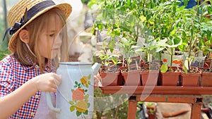 Adorable little girl kid in hat watering seedlings