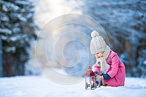 Adorable little girl with latern in frozen forest on Christmas at winter day