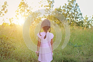 Adorable little girl laughing in a meadow - happy girl at sunset