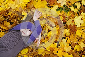 Adorable little girl laying on golden maple leaves